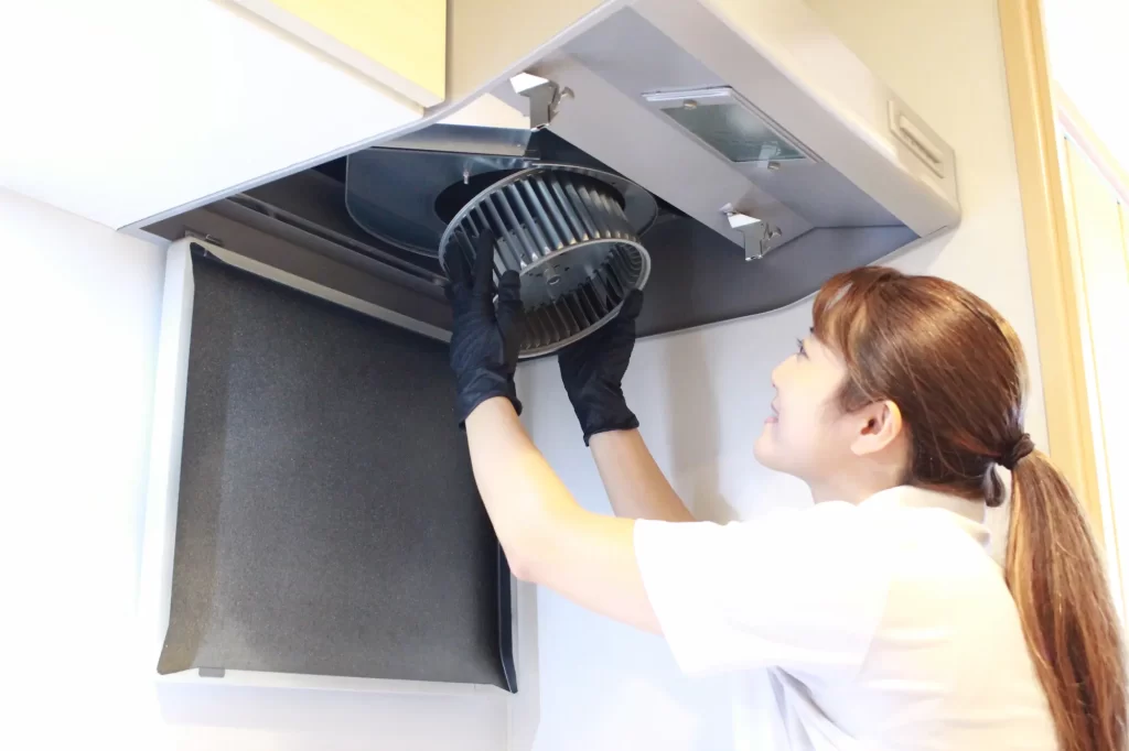 スタッフがレンジフードクリーニングを行う様子