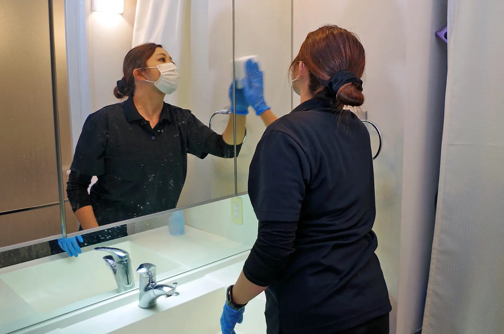 スタッフが洗面台をクリーニングする様子